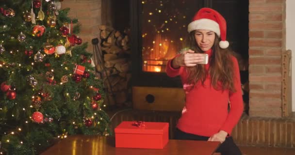クリスマスツリーで自宅で新年を祝い 携帯電話で自分撮り写真を撮る女性のビデオ — ストック動画