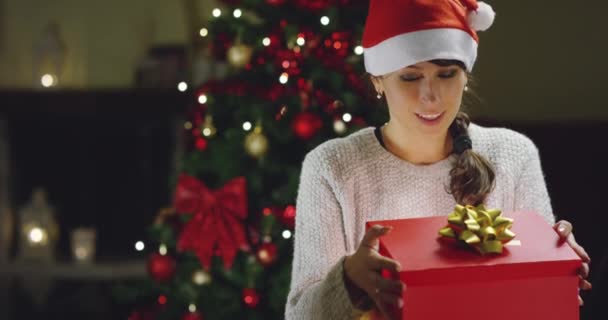 Видео Счастливой Женщины Шляпе Санта Клауса Открывающей Подарочную Коробку Елке — стоковое видео