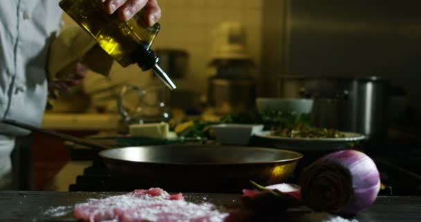 クローズアップビデオ シェフが肉を調理し フライパンに油を注ぐ — ストック動画