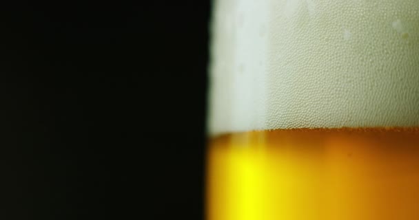 黒の背景に泡とガラスの軽いビールのビデオ — ストック動画