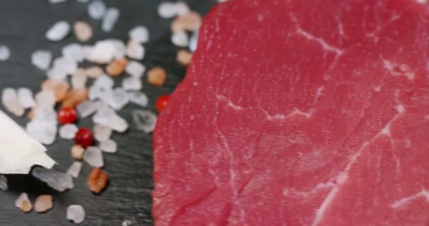 美しいジューシーな新鮮な肉ステーキ塩 ローズマリー ニンニク 黒の背景 上面にトマトのテーブルの上 コンセプト 自然製品 バイオ製品 肉製品 オーガニック — ストック動画