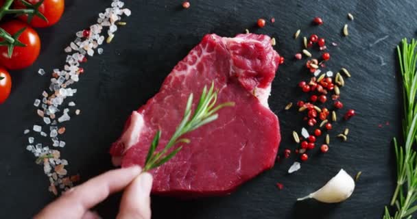 schöne saftige Steak mit frischem Fleisch auf einem Tisch mit Salz, Rosmarin, Knoblauch und Tomaten auf schwarzem Hintergrund, Draufsicht. Konzept: Frische  Naturprodukte, Bioprodukte, Fleischprodukte, Bio, Ernährung.