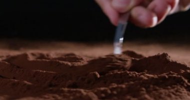Süper ağır çekim kakao tozu dozaj, küçük bir kaşıkla 4 k siyah bir zemin üzerine izole (makro kapat)