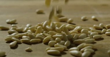 eller genç Şef yavaşça aşırı ağır çekimde çam fıstığı tahta arka plan ile bir ahşap kesme tahtası üzerinde küçük bir grup dinlenme.