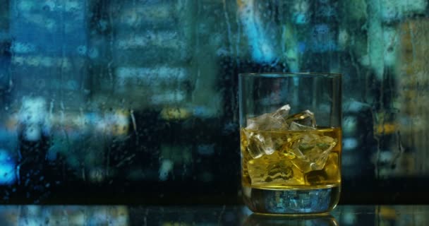从摩天大楼的窗户上 一个人喝着苏格兰威士忌 在背景中 你可以看到下雨的纽约景色 威士忌 — 图库视频影像