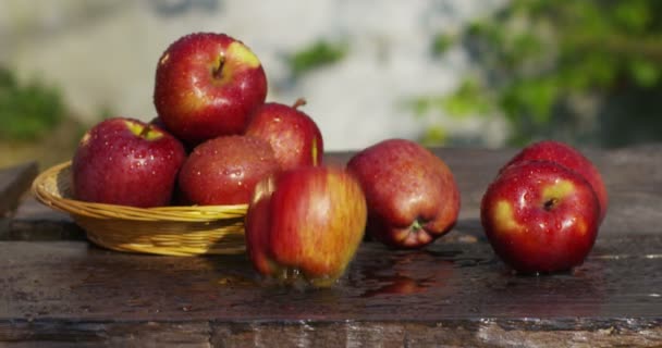 新鮮でおいしい赤リンゴ落ちる木製のテーブルとバック グラウンドでキャンペーン — ストック動画