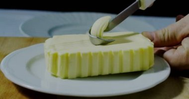 Beyaz çanak üzerinde bir bıçakla kırbaçlanan tereyağı süper ağır çekim makro (yakın)