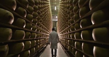 depoda raflarda Parmesan peyniri arasında yürüyen adam video