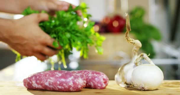 慢动作视频厨师手拿着绿色草药新鲜欧芹在餐桌上与肉类和大蒜 — 图库视频影像