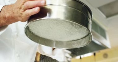 Bir profesyonel mutfak ağır çekimde yemek pişirmek için kullanmadan önce kirleri çıkarmak için beyaz un eleme bir İtalyan Şef. İtalyan gıda ve gurme, sağlıklı beslenme ve biyografi kavramı.