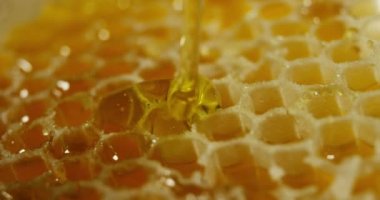 bir kavanoz içinde biyolojik ve hakiki bal damlar. Damlayan bal petek. siyah arka plan ve ahşap bir masa. Tatlım slowmotion içinde düşer ve Avustralya'dan arıları tarafından yapıldı.