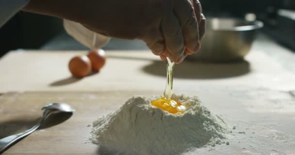 小麦粉に落ちる黄身で卵を割るシェフのスローモーションビデオ — ストック動画