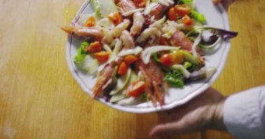 ahşap masa yüzeyinde tabakta pişmiş deniz ürünleri salatası sunan garson video