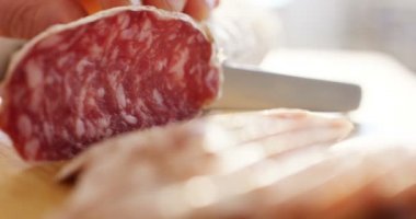 Profesyonel bir mutfakta deneyimli bir aşçı mevsimi keser. İtalyan salam sosisi çok ince dilimlerle profesyonel bir bıçakla kesilir. Doğa, İtalya, gıda, diyet ve biyoloji kavramı.