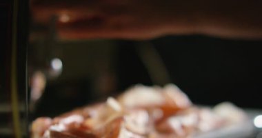 Genç deneyimli dilimleri Parma jambonu İtalyanca ama çok iyi ve o tadı ve İtalya nın iyiliği savored, parma jambonu karanlık gölgeler ile ortam profesyonel bir makine tarafından düzenlenen