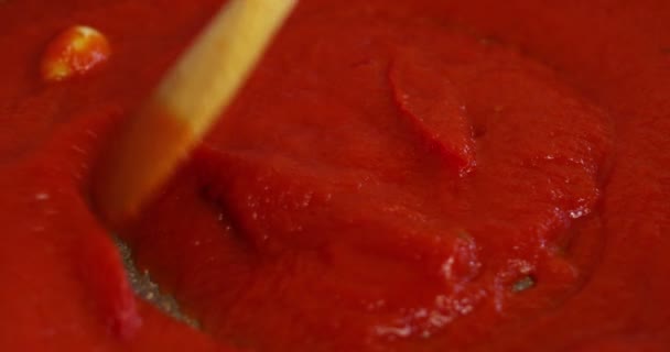 Un chef dans une cuisine professionnelle, mélanger la sauce de tomate rouge avec une cuillère en bois.Concept alimentation, nourriture, italien et nutrition .