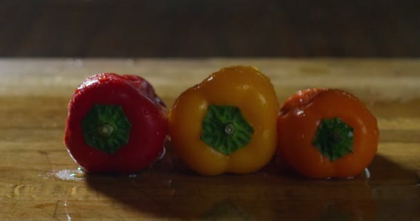 在木制切菜板上跳跃和弹跳的塔利班彩色辣椒以极慢的动作 以采取一个平衡的位置 — 图库视频影像