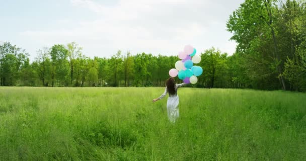 在草地上与五颜六色的气球运行的妇女慢动作视频 — 图库视频影像