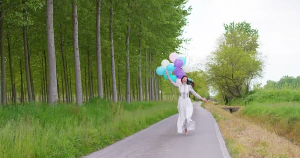 在柏油路上用五颜六色的气球奔跑的快乐的妇女的慢动作视频 — 图库视频影像