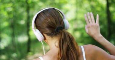 Arkadan görünüm, kadın müzik dinleme Kulaklığımda dans ve yaz orman ağaçları ile rahatlatıcı video 