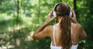 kulaklıklar müzik dinleme ve yaz ormandaki ağaçlar, arkadan görünüm ile rahatlatıcı kadın video 