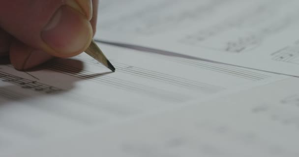 ビデオでは 紙のシート上の曲のメロディー メモを書くソング ライターの人のショットをクローズ アップ — ストック動画