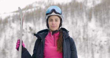 koruyucu kask ve kayak gözlüğü giyiyor, kayaklar tutan ve kameraya bakarak kış içinde kadın video 