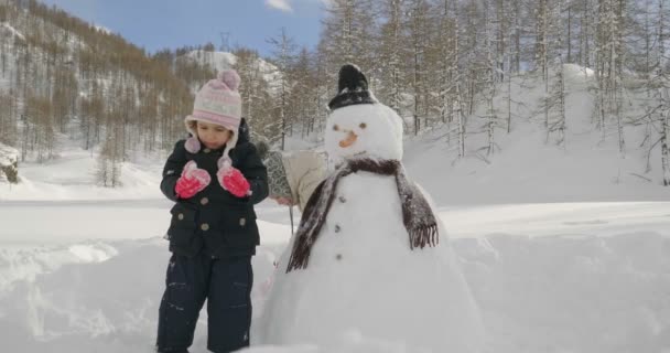 冬の日 雪のある山の二人の少女を再生し 雪だるまを再生します 冬の休日 ゲーム クリスマス — ストック動画