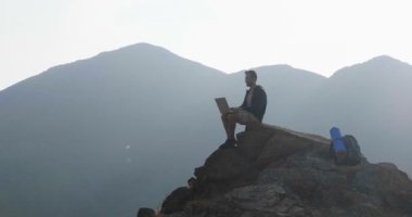  ağır çekim video uzun yürüyüşe çıkan kimse gezgin adam dağın tepesinde oturan ve doğada dizüstü bilgisayar kullanarak 