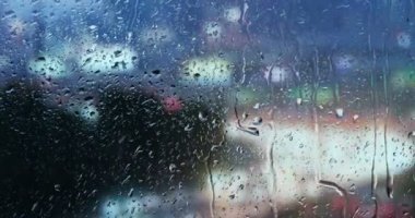 Bir evin penceresinden cama düşen yağmur görebilirsiniz ve arka plan bulanık bir bina, makine ve trafik veya fırtına ya da fırtına olduğunu.