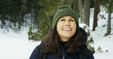ağır çekim bir kız ormanın içinden ve karda yürür, saf hava, dağın doğada gülümsüyor, sırt çantası hiking ile yürüyor. Kavram: gevşeme, yürüyüş, aşk, saflık, özgürlük