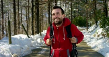 gülümseyen, kırmızı ceket ve sırt çantası kış ormanda giyen mutlu uzun yürüyüşe çıkan kimse gezgin adam video 