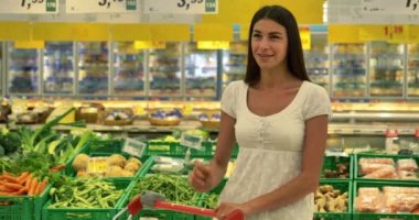 Güzel bir genç kız (kadın) markette, beyaz kolsuz bluz içinde süpermarket, seçtiği bir sepeti ile alkollü içecekler ürünler. Konsept: satın ürünler, büyük alımları, market, mağaza, ürünler.