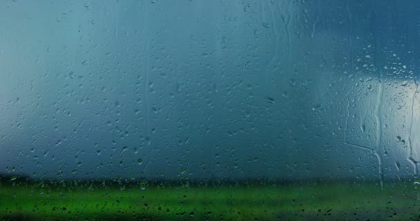 家の窓からガラスの雨を見ることができ 背景をぼかした写真は建物 機械やトラフィックまたは嵐雷雨 — ストック動画