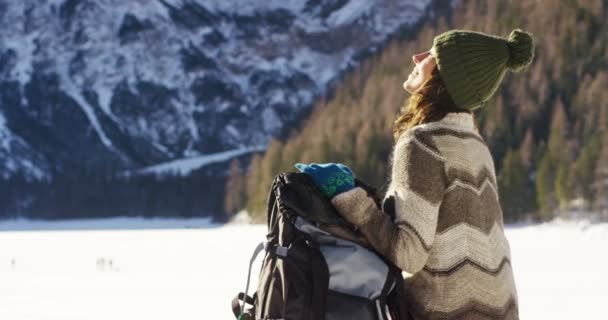 女の子は かかっているし 彼の腕の中で雪の中歩くハイキング バックパックを保持している彼の前に雪の山を見てリラックスします コンセプト リラクゼーション ハイキング — ストック動画