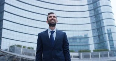 Açık havada başarı kutluyor ve modern cam ofis binası, poz büyük ihale takım elbise ve boyun kravat mutlu beyaz işadamı ağır çekim video 