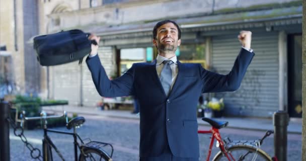 视频快乐的高加索商人庆祝成功的户外和举行案件袋 街道与自行车在背景 — 图库视频影像