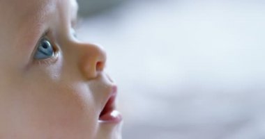 Bir bebek, büyük mavi gözleri ve açık renk saçlı, bir çocuk oturur ve bembeyaz bir battaniye var gülümsüyor, beyaz zemin üzerine annesi bakar. Konsept: çocuk, çocuk, Bebek, bebekler, yeni nesil.