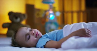 güzel anne bebeği uyku önce açık bir öpücük vermek ve onu çok tatlı bir battaniye pembe ve mavi yün malzeme, sıcak kavramı ve sağlık ile kapak