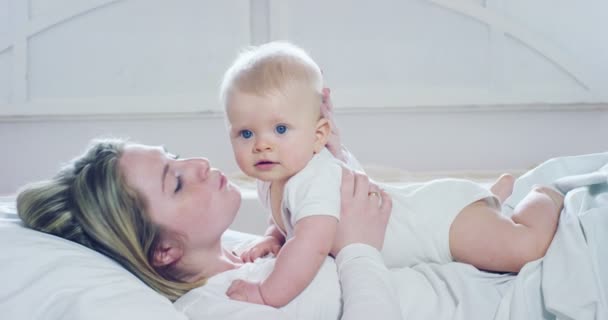 生命中最美好的时刻 一位充满爱的快乐年轻母亲在白色的背景上 用雪白的毯子抱着一个哺乳的儿子 家庭和幸福的概念概念 — 图库视频影像