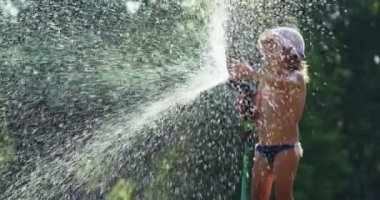 Güneşli sıcak bir gün, bir bebek su ile oynayan ve zevk çok su ile banyo. Bebek çok mutlu ve su soğuk olduğundan gülümseyen.