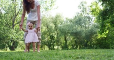 Anne ve küçük kız mutlu oynamak doğada, Anne kucağında bebeği alır ve rahatla, 4 k uhd bir güneş bir aile olarak birlikte olmak mutlu