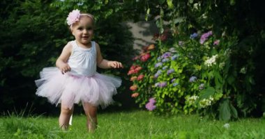 güneşli bir yaz günü A yeni doğan gülümseyen anne mutlu doğru çalışan ilk adımı alır. Hayatında hiç unutmayacak ilk adımlar. Ve annem ona ilk adımlar atmaya yardımcı olur.