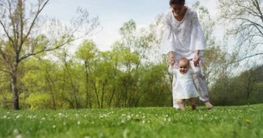 Anne ve küçük kız mutlu oynamak doğada, Anne kucağında bebeği alır ve rahatla, 4 k uhd bir güneş bir aile olarak birlikte olmak mutlu