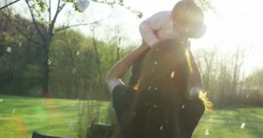 Anne ve küçük kız mutlu oynamak doğada, Anne kucağında bebeği alır ve rahatla, 4 k uhd bir güneş bir aile olarak birlikte olmak mutlu