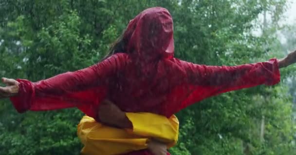幸福的情侣们穿着红色和黄色的外套 在雨中拥抱 旋转的视频 — 图库视频影像
