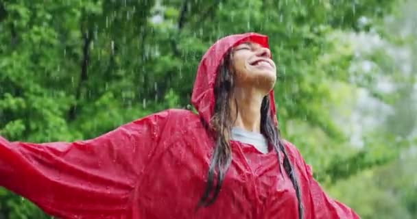 雨の下での周りの回転の赤いコートを着て笑顔の女性のスロー モーション ビデオ — ストック動画