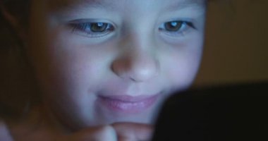 Çocuk akşam veya gece akşam ışığı, e-öğrenme, öğrenme ve basit teknolojileri kavramı ile tablet veya telefon kullanır. Çocuk ve uygulanan teknolojiler futuristik konsepti.