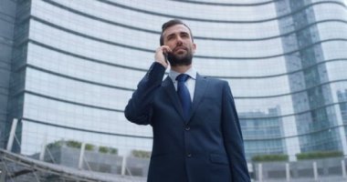 Telefonlara bir işadamı göndermek mesajları ve güzel iş Haberler için gülümsüyor ve arka planda bir kişi görmek. Konsept: teknoloji, telefon, iş gezileri, iş, wall street