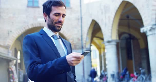 Ein Geschäftsmann Telefon Sendet Nachrichten Und Lächelt Für Die Schönen — Stockvideo